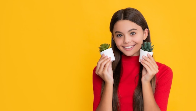 Positive kid with cactus in pot on yellow background