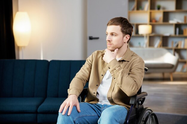 Foto cura positiva dello stile di vita per la riabilitazione e il sostegno delle persone disabili a casa giovane uomo caucasico in sedia a rotelle in soggiorno