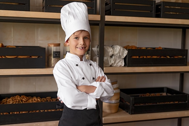 Positive little baker standing near shelves