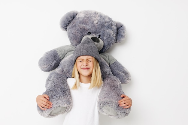 Positive little girl teddy bear in the hands of fun kids\
lifestyle concept