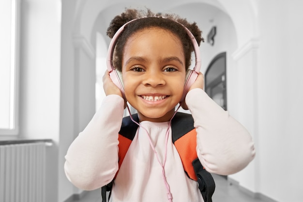 Bambina positiva che indossa le grandi cuffie rosa