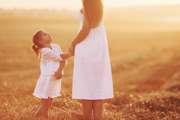 positive little girl with her mother have weekend outdoors on the summer field together