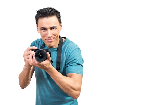 Positive male photographer taking picture on professional photo camera while looking at camera on white isolated background