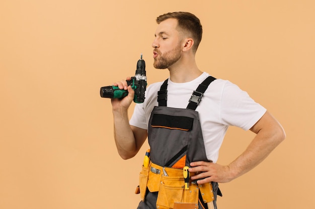 Positive male repairman at home with screwdriver on beige background