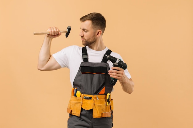 Positive male repairman at home with tools on beige background