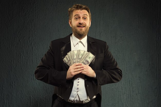 Positive man in a tailcoat hold money.