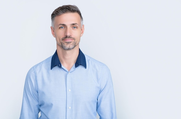 Positive mature businessman in office shirt on grey background