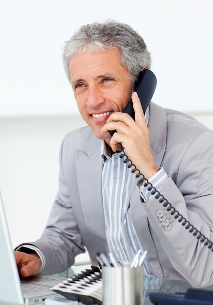 Positive mature businessman talking on phone