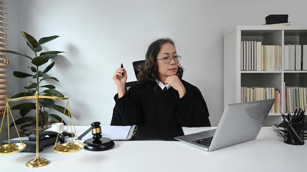 Positive mature female judge talking to her clients for providing law consultation and legal advice online