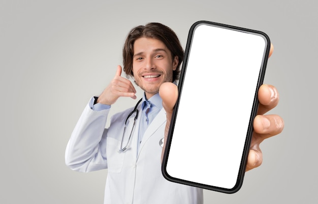 Positive medical specialist showing call gesture and smartphone