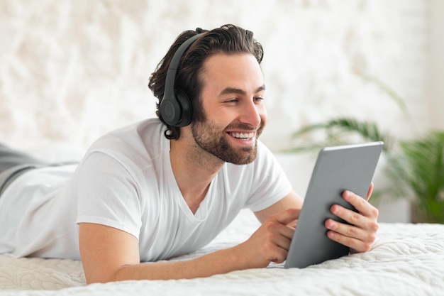 Positive millennial guy enjoying brand new wireless headset