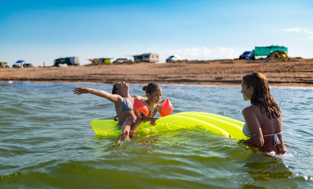 Positive mom is relaxing at sea with her two little daughters on a sunny summer day. The concept of a summer holiday at sea and summer vacation