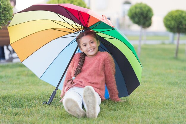 Positive mood in autumn rainy weather Little girl under colorful umbrella Rainbow after rain Multicolored umbrella for little happy girl Optimist and cheerful child Spring style Rainbow parasol