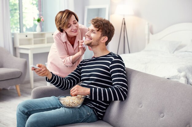 Positive mood. Joyful happy man smiling while enjoying the care of his mother