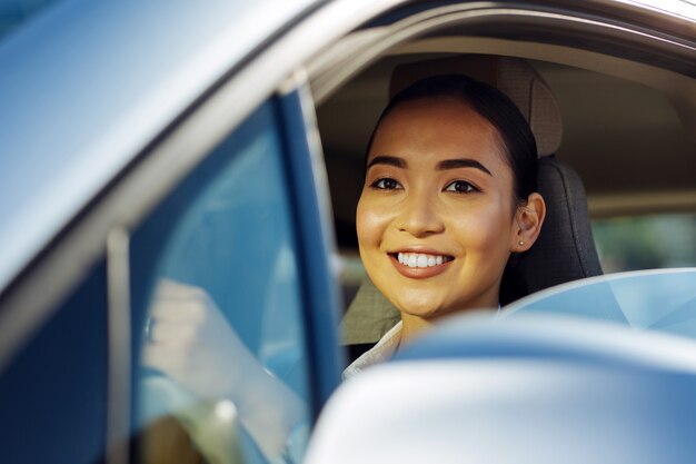 ポジティブな気分。彼女の車を運転しながら笑顔の楽しい素敵な女性