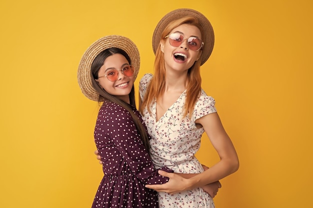 Positive mother and child in straw hat on yellow background