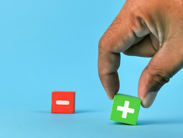 Positive and negative part concept. Hand pick and choose plus symbol on wooden cube