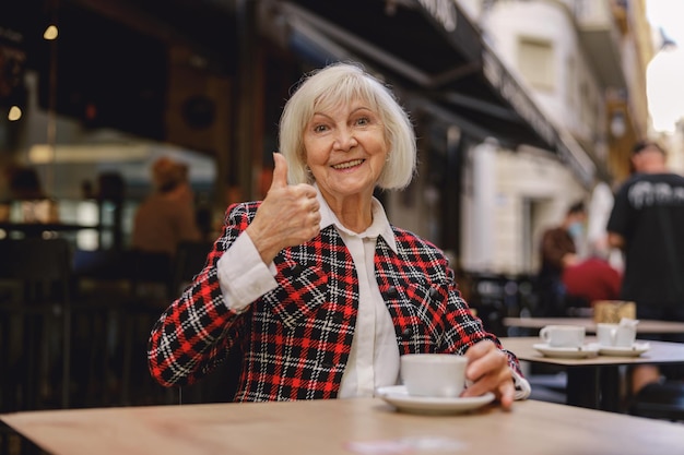 Donna positiva del pensionato che mangia caffè al caffè