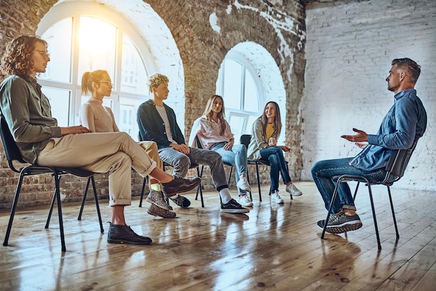 Le persone positive che si siedono sulle sedie prendono parte a sessioni di terapia di team building per cercare di risolvere i problemi