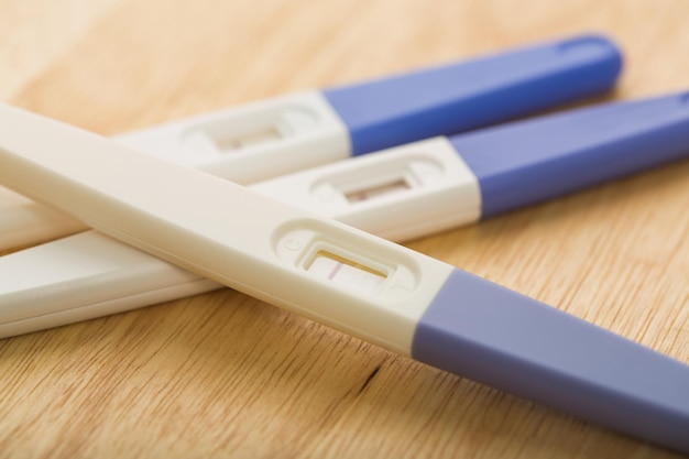 positive pregnant tester on wooden table close up