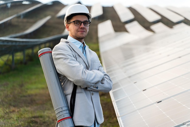 Positive professional engineer in jacket posing at the photo camera near the solar panel