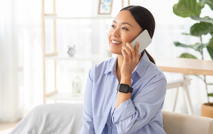 Photo ポジティブでリラックスした若いアジア人女性が電話で会話をしています