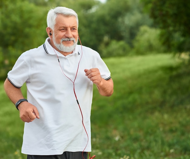 Photo positive running old man in green city park.