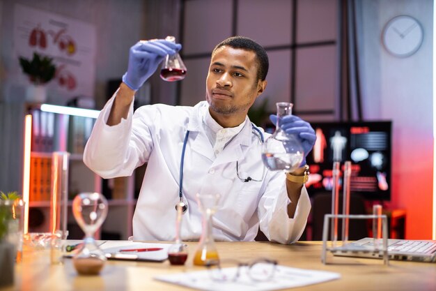 Photo positive smart enthusiastic african american man scientist looking at the test tubes