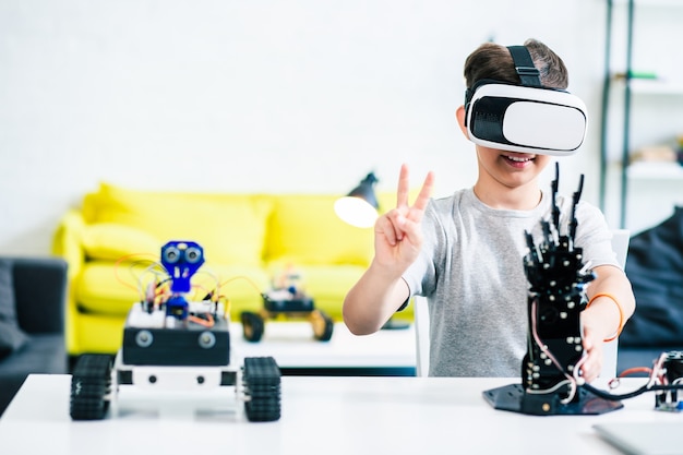 Ragazzino intelligente positivo che prova i suoi occhiali vr mentre indossa occhiali vr