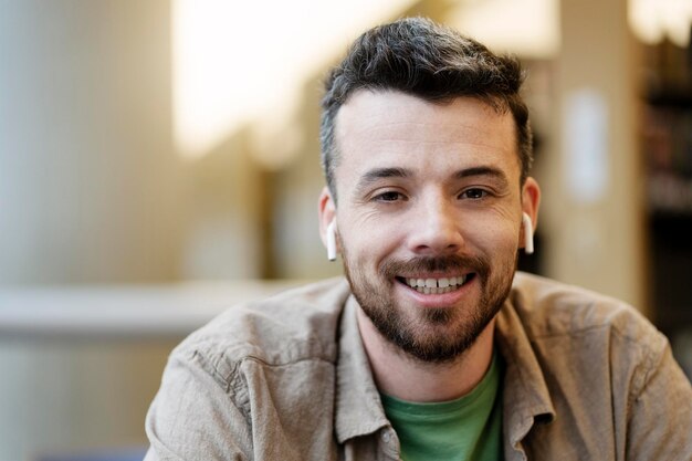 positive smiling man in wireless headphones sitting looking at camera