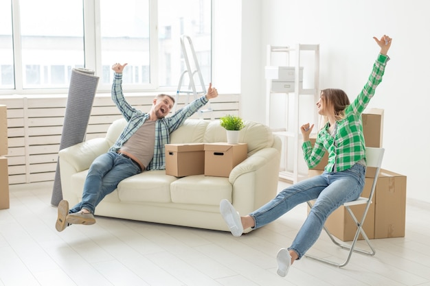 Positive smiling young girl sitting against her laughing in a new living room while moving to a new