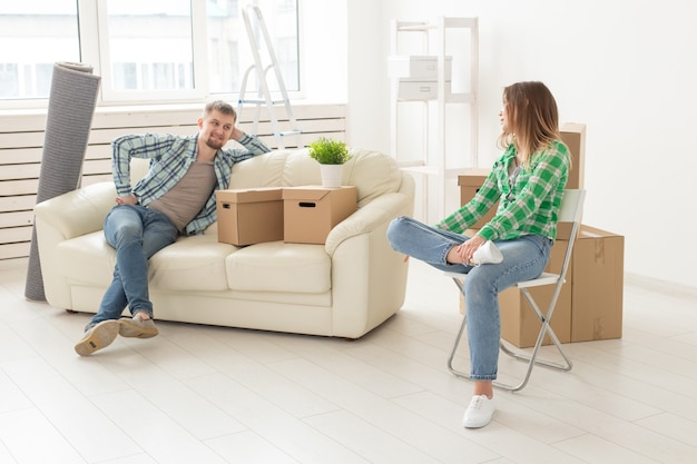 Positive smiling young girl sitting against her laughing in a new living room while moving to a new