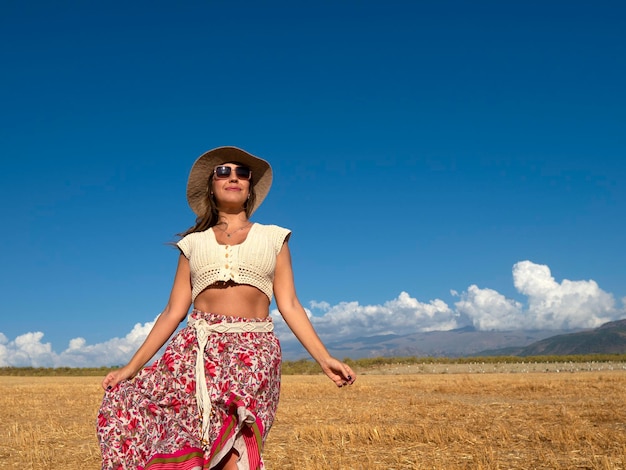 Positive stylish female walking in field