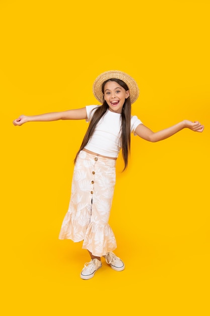 Positive teen girl in straw hat having fun on yellow background