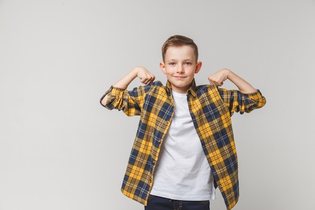 Ragazzo adolescente positivo che mostra la forza del corpo.