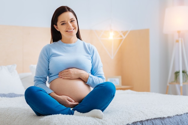 Позитивные мысли. Радостная беременность, выражающая позитив и обнимающая живот
