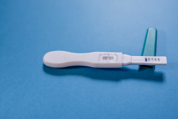positive white plastic pregnancy test isolated on blue background.