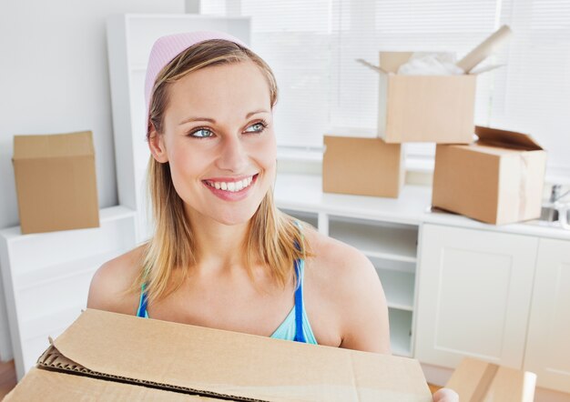 Positive woman carrying boxes at home