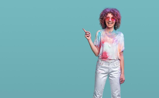 Positive woman in holi colors pointing away