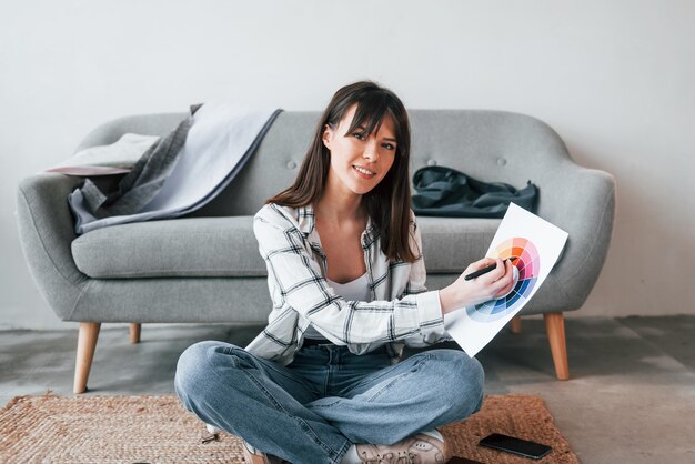 ポジティブな女性が笑っている若い女性のフリーランスの労働者は、昼間は家の中で屋内にいます