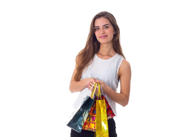 Positive woman in white blouse and black skirt holding shopping bags and jumping in studio