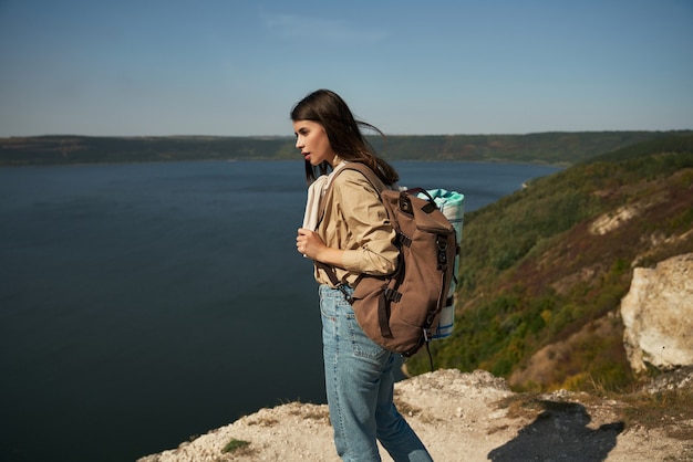 Positive woman with backpack looking at dniester river