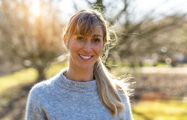 Positive woman with charming smile looks into camera Girl in gray outfit posing in a park at spring