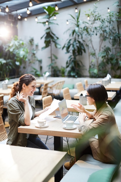 カフェでレポートを分析する肯定的な女性