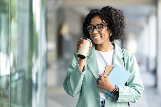 Photo positive young black woman going to work drinking takeaway coffee