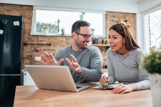 Positive young couple looking at laptop and talking.