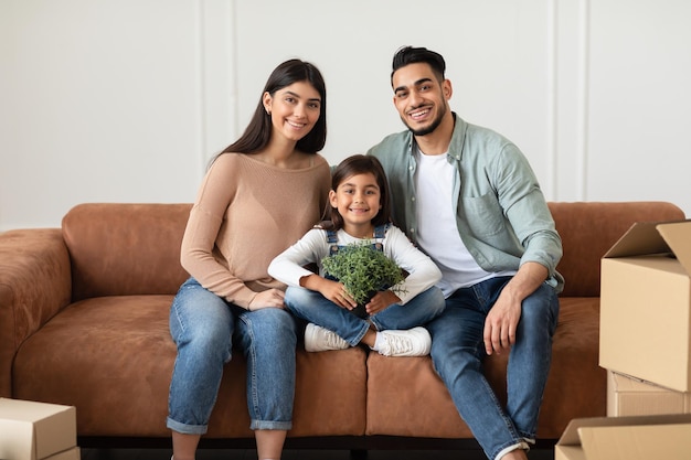 Positive young family looking at camera, posing on couch