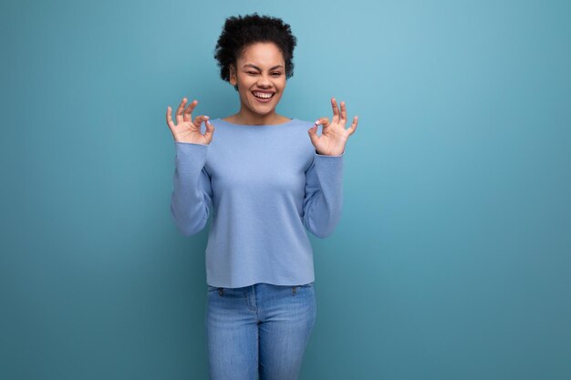 Positive young latin s woman with black hair tied in a bun on a blue background