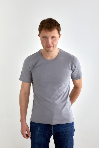 Positive young man in casual outfit standing on gray background