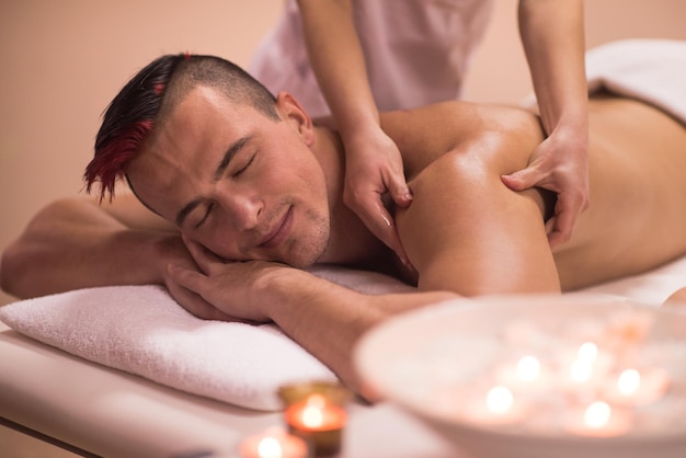 Positive young man having a back massage in a spa center